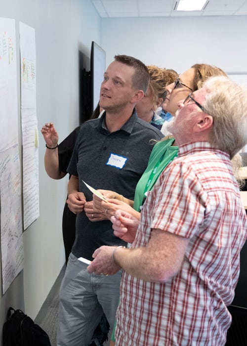 A group of employees looks at a planning board together