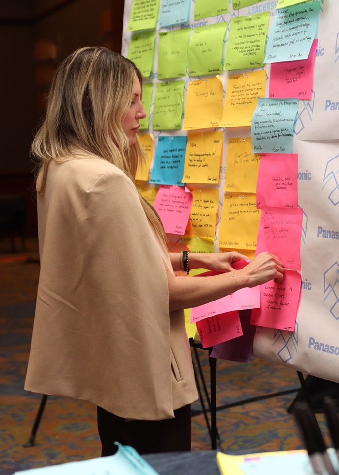 A woman posts on a team vision board with sticky note